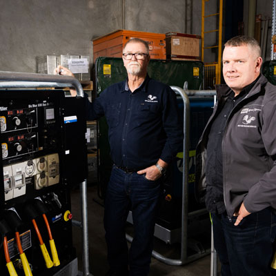 2 guys standing around a welding machine… in another location