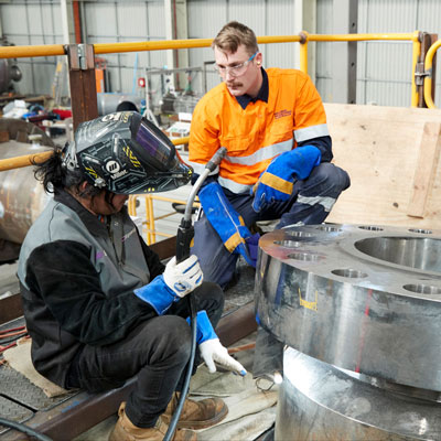 A welder with a worker next to them in hi-vis